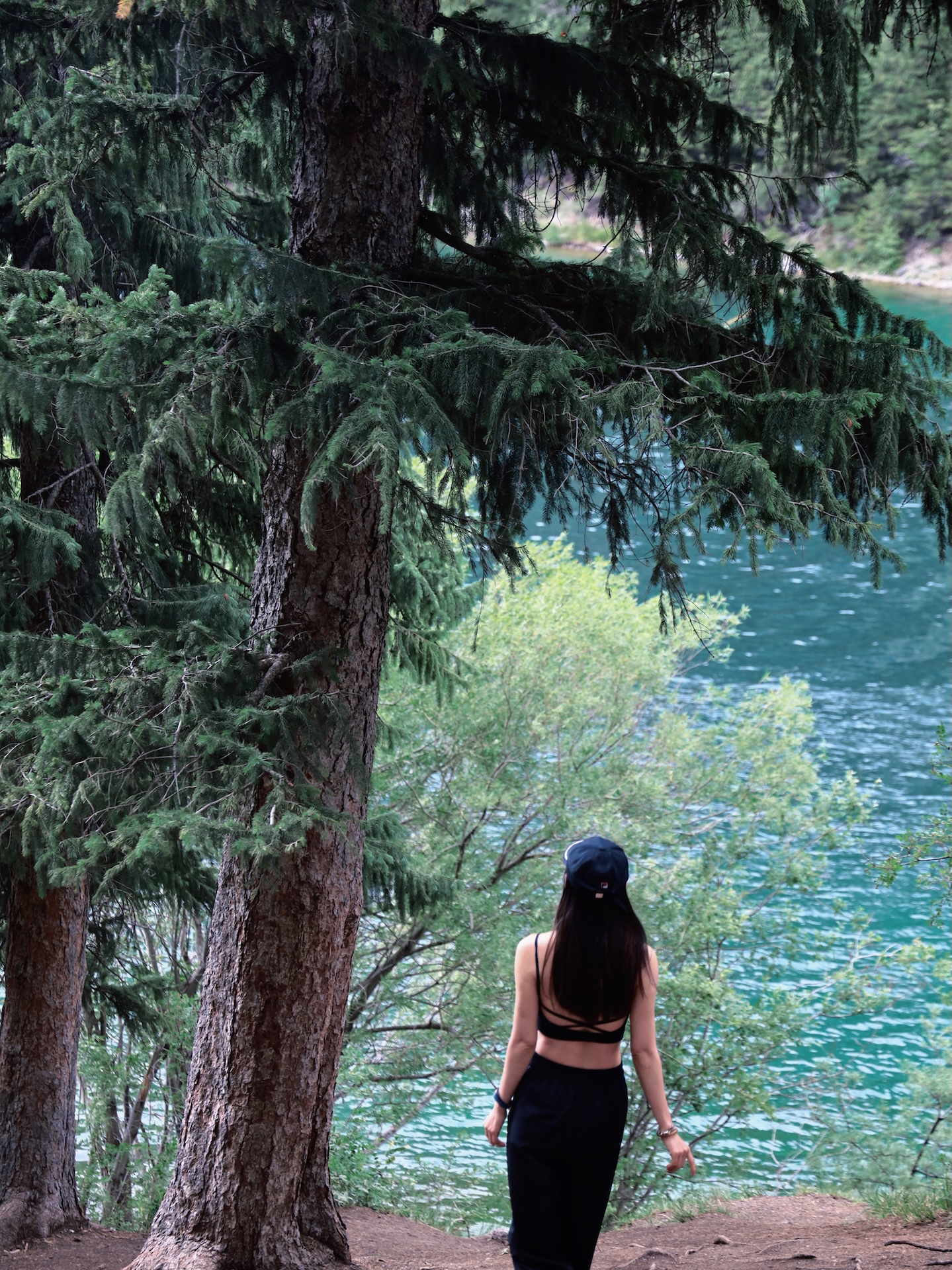 Angela walking through pine trees beside Kolsay Lake
