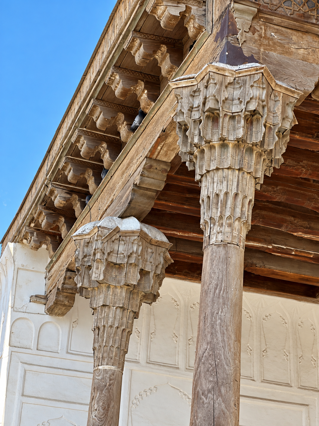 Close-up of carved wooden column capitals and roof details photographed during a visit to the Ark of Bukhara
