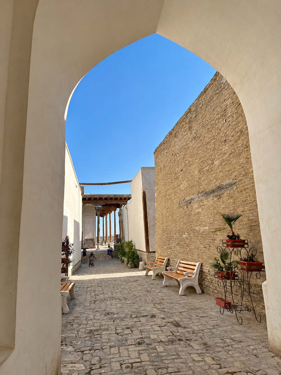 View through a white archway into a cobbled passage inside the Ark of Bukhara