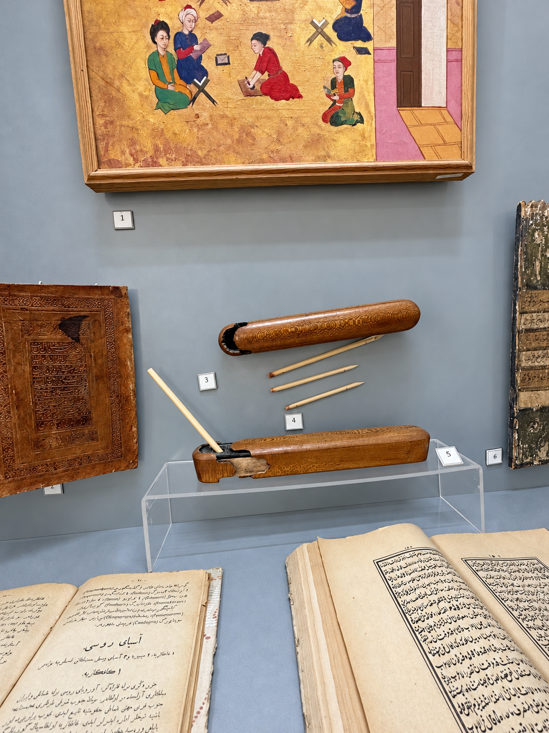 Manuscripts, reed pens, and decorated writing cases displayed in the Ark of Bukhara museum