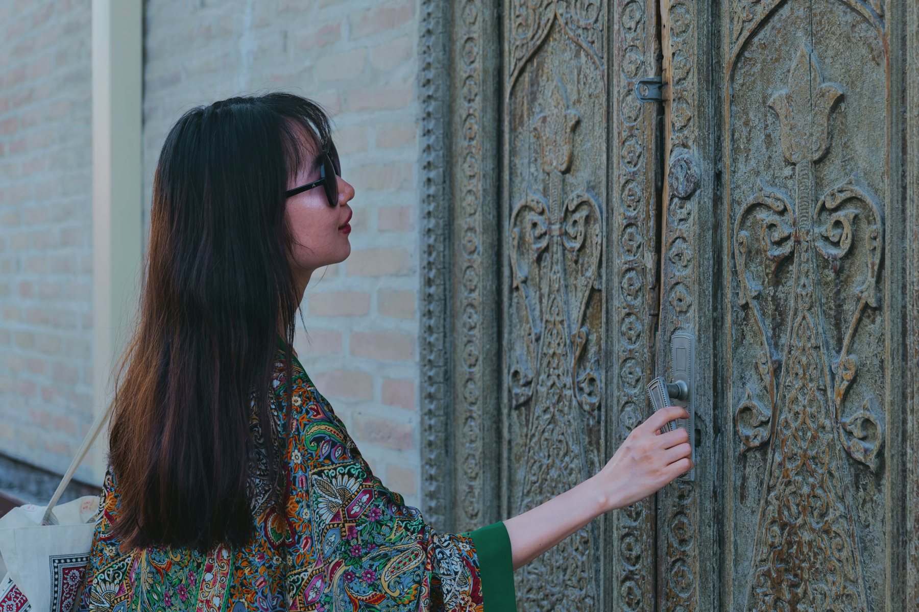 Angela Jia beside a carved wooden door in Bukhara’s old town