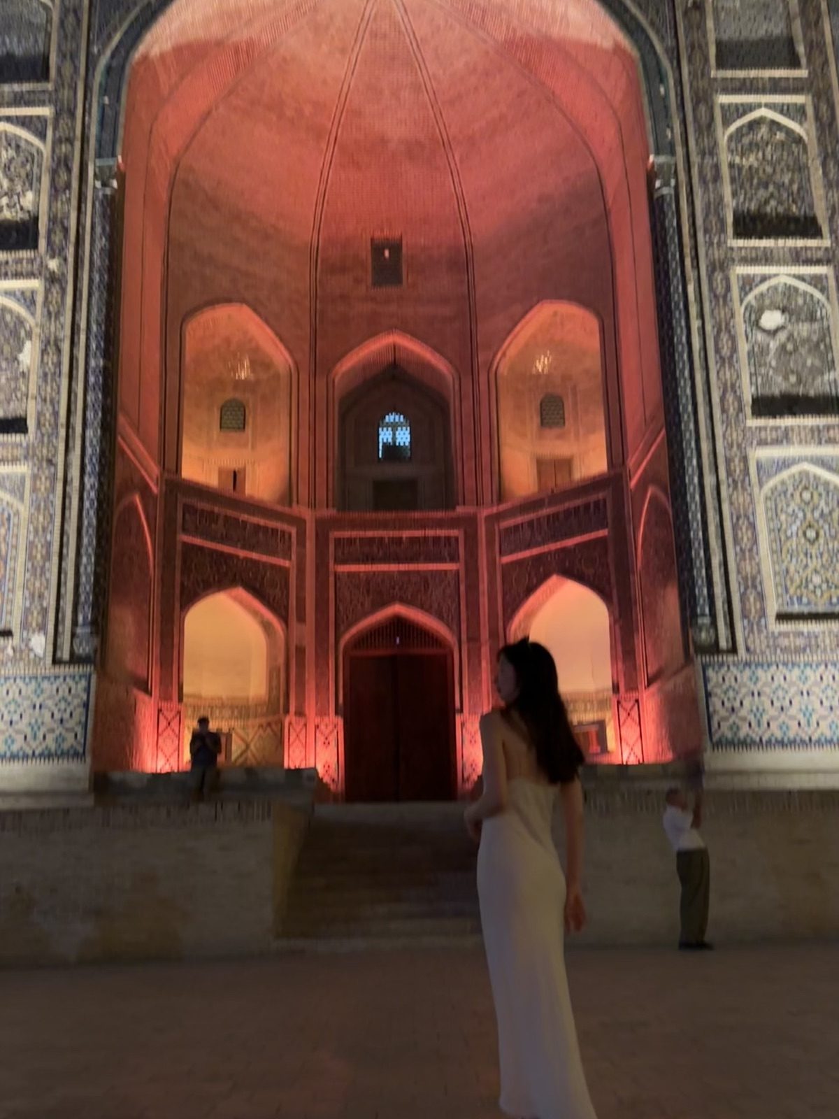A traveler in front of an illuminated entrance in Bukhara