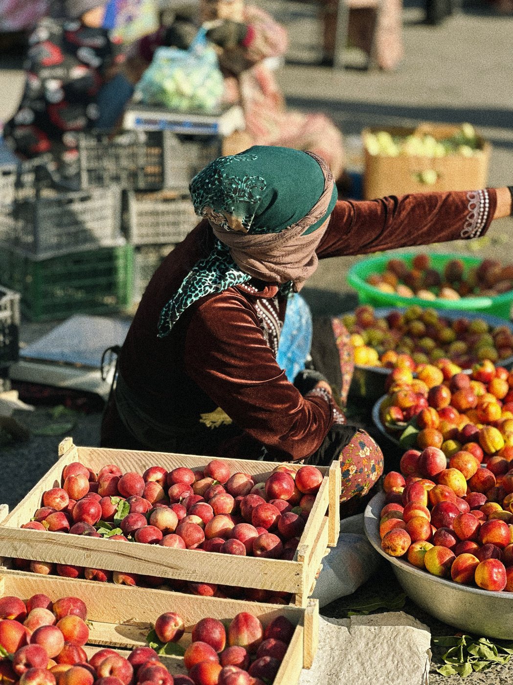 A fruit seller surrounded by peaches at a Bukhara market