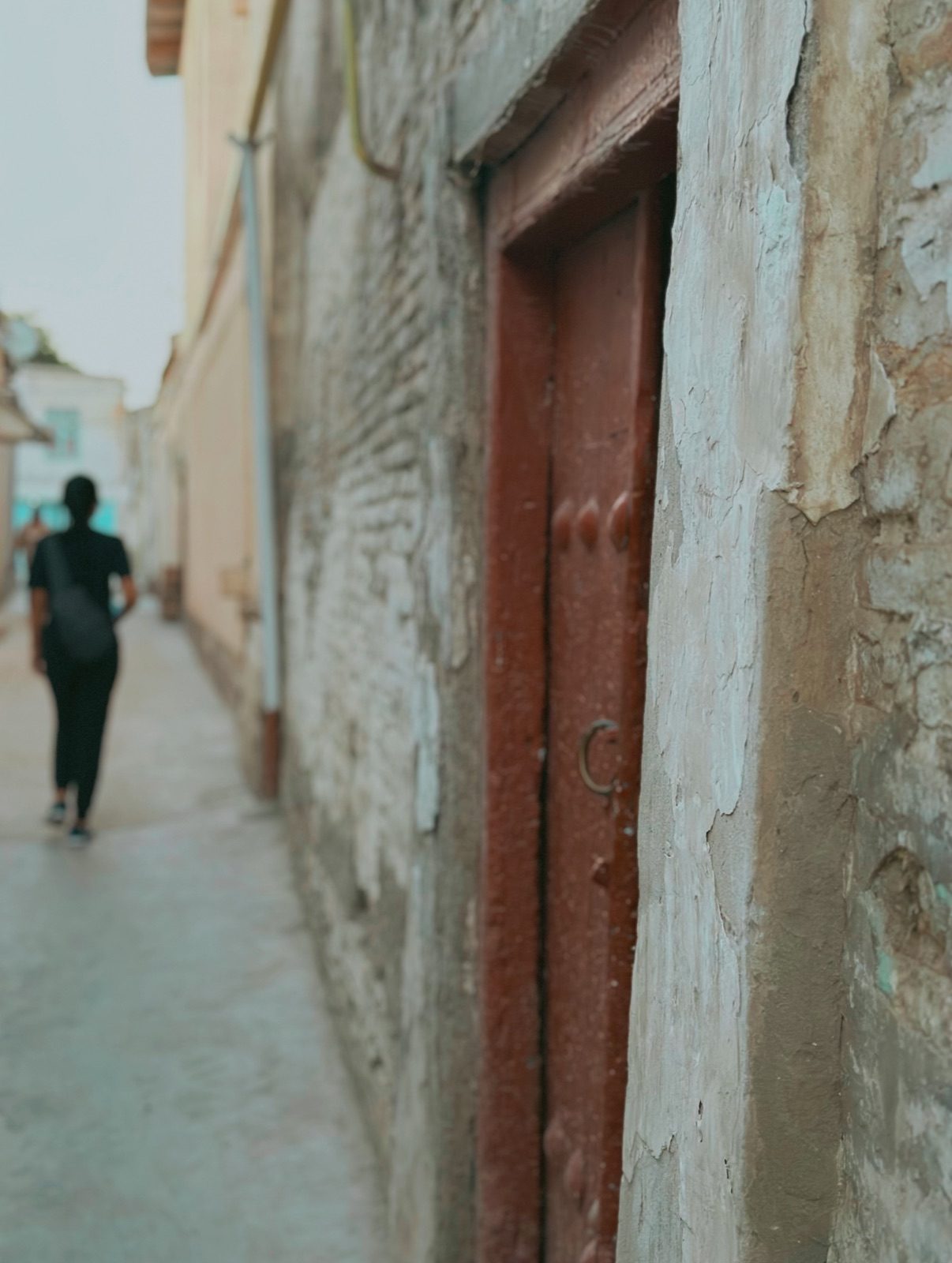 A narrow old town lane with a weathered wooden door in Bukhara