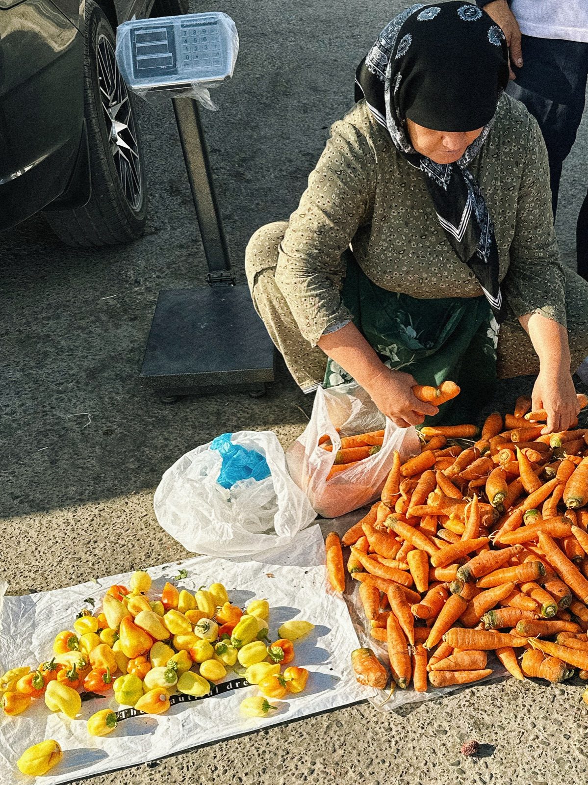 A vegetable seller with carrots and peppers at a Bukhara market